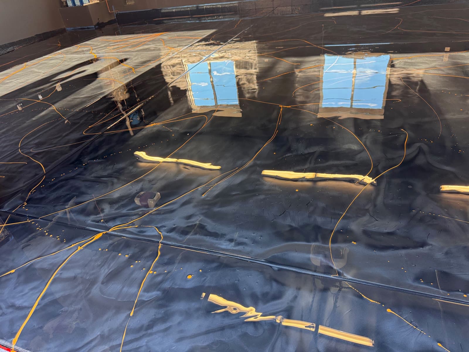 Black metallic epoxy with gold veining being poured in an Escondido garage