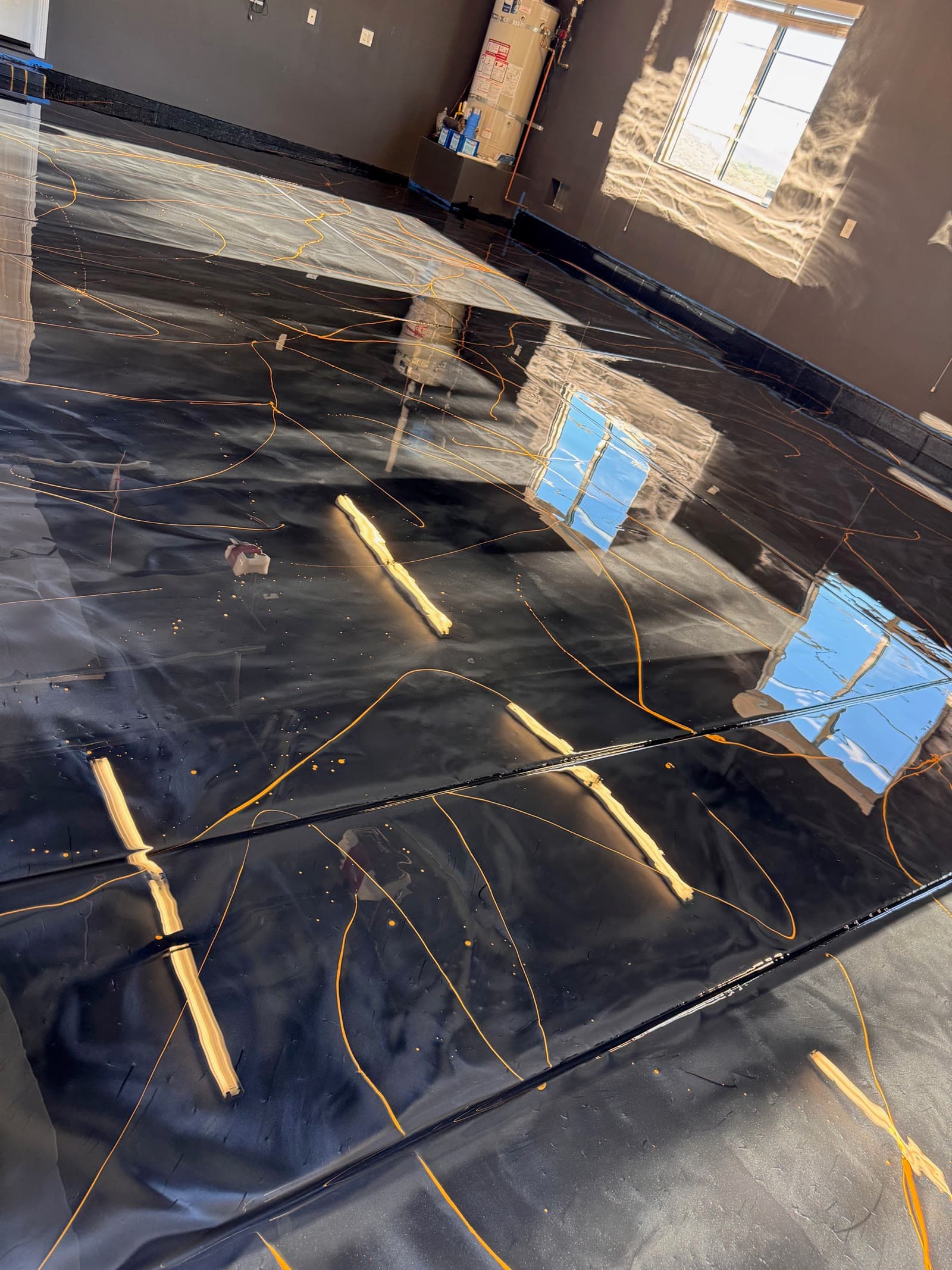 Wet black and gold metallic epoxy spreading across a garage slab in Escondido