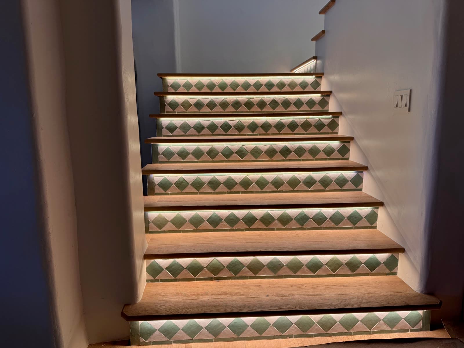 Full flight of oak stairs with green diamond tile risers lit from beneath each tread