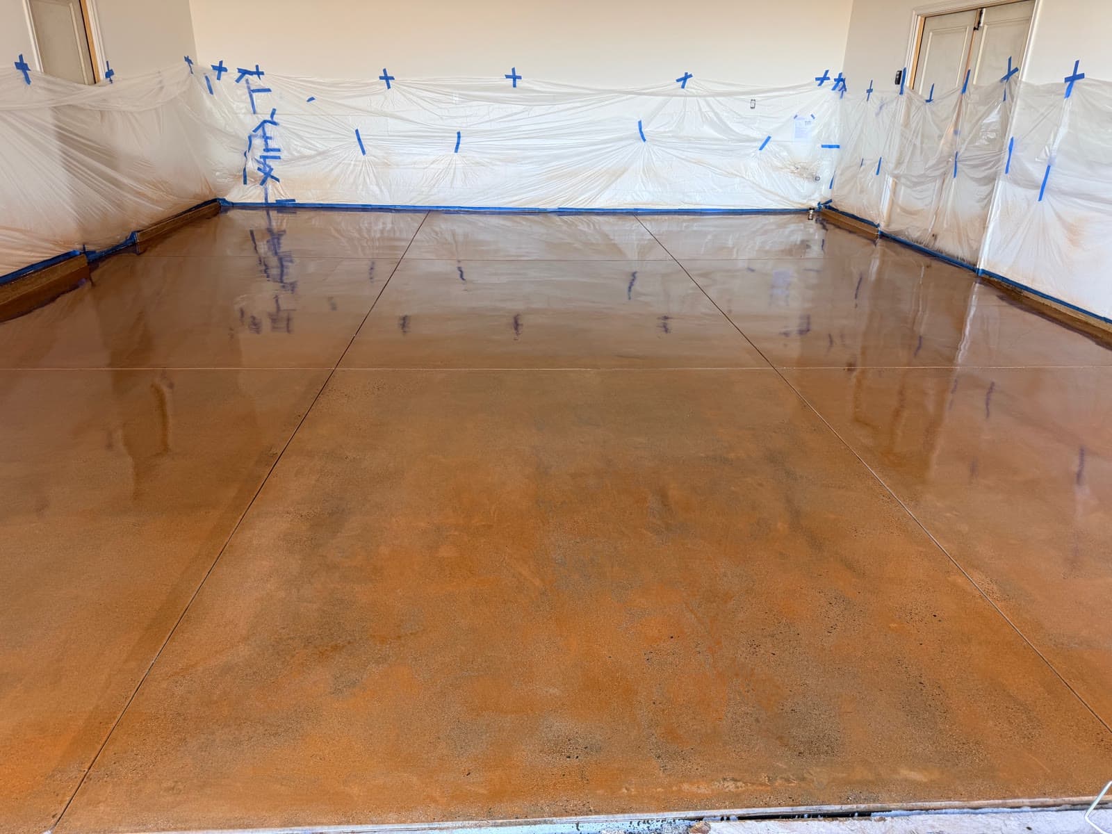 Amber acid-stained and sealed concrete floor in a San Marcos room with walls masked off