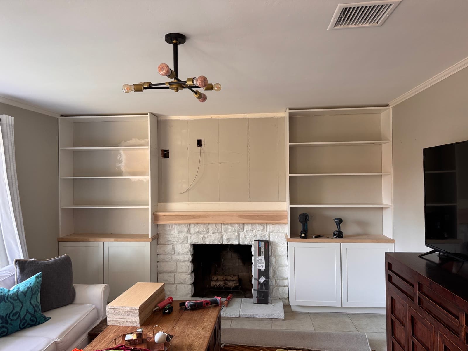 White oak mantel and built-in cabinetry around a whitewashed brick fireplace in Carlsbad