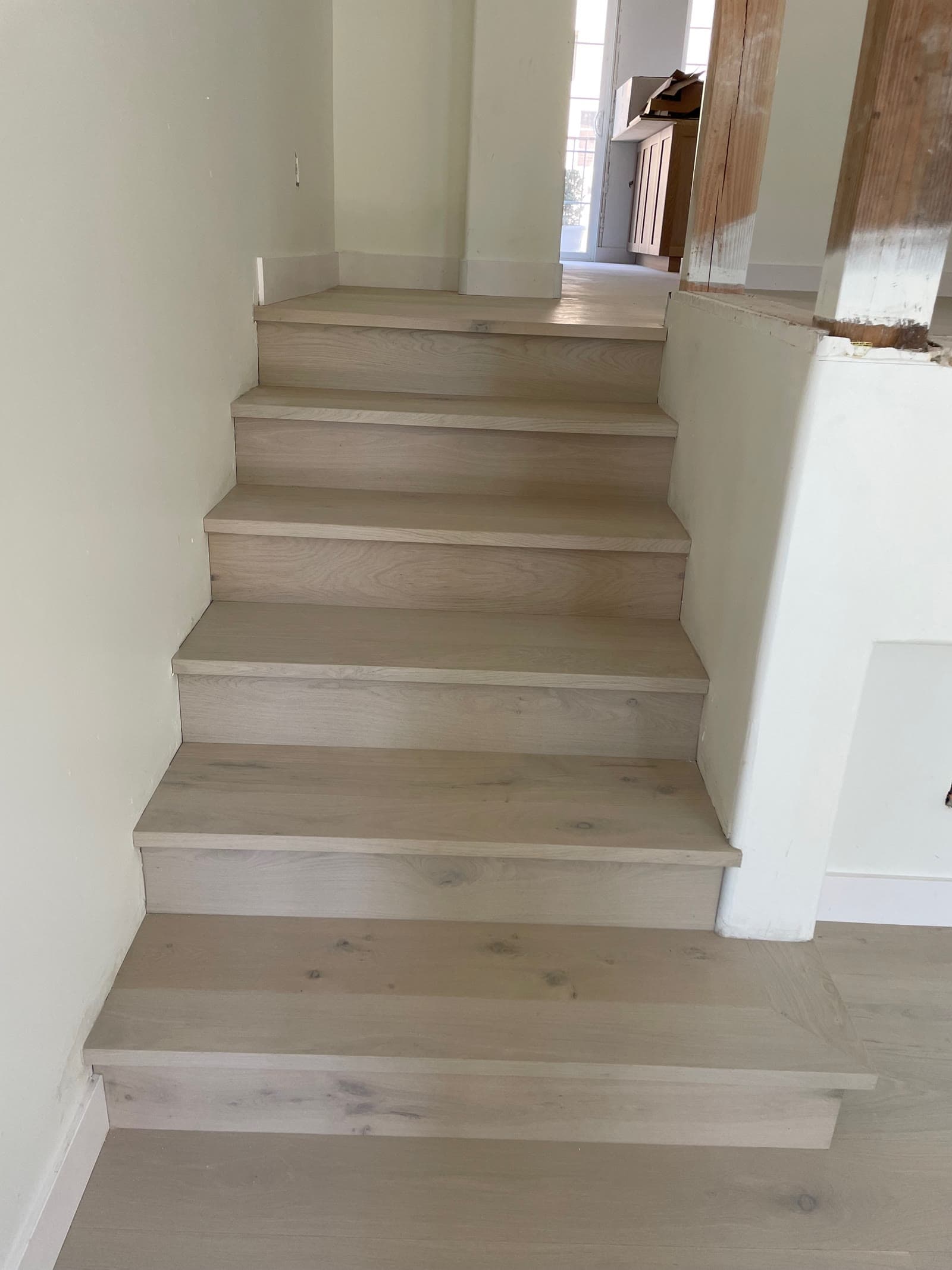 Limed white oak stair treads and risers running down to a matching plank floor in Carmel Valley