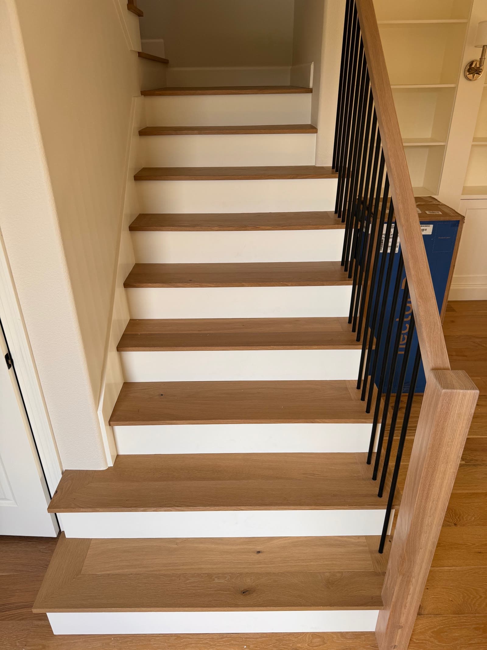 Natural white oak stair treads with white painted risers and black iron balusters, Carmel Valley