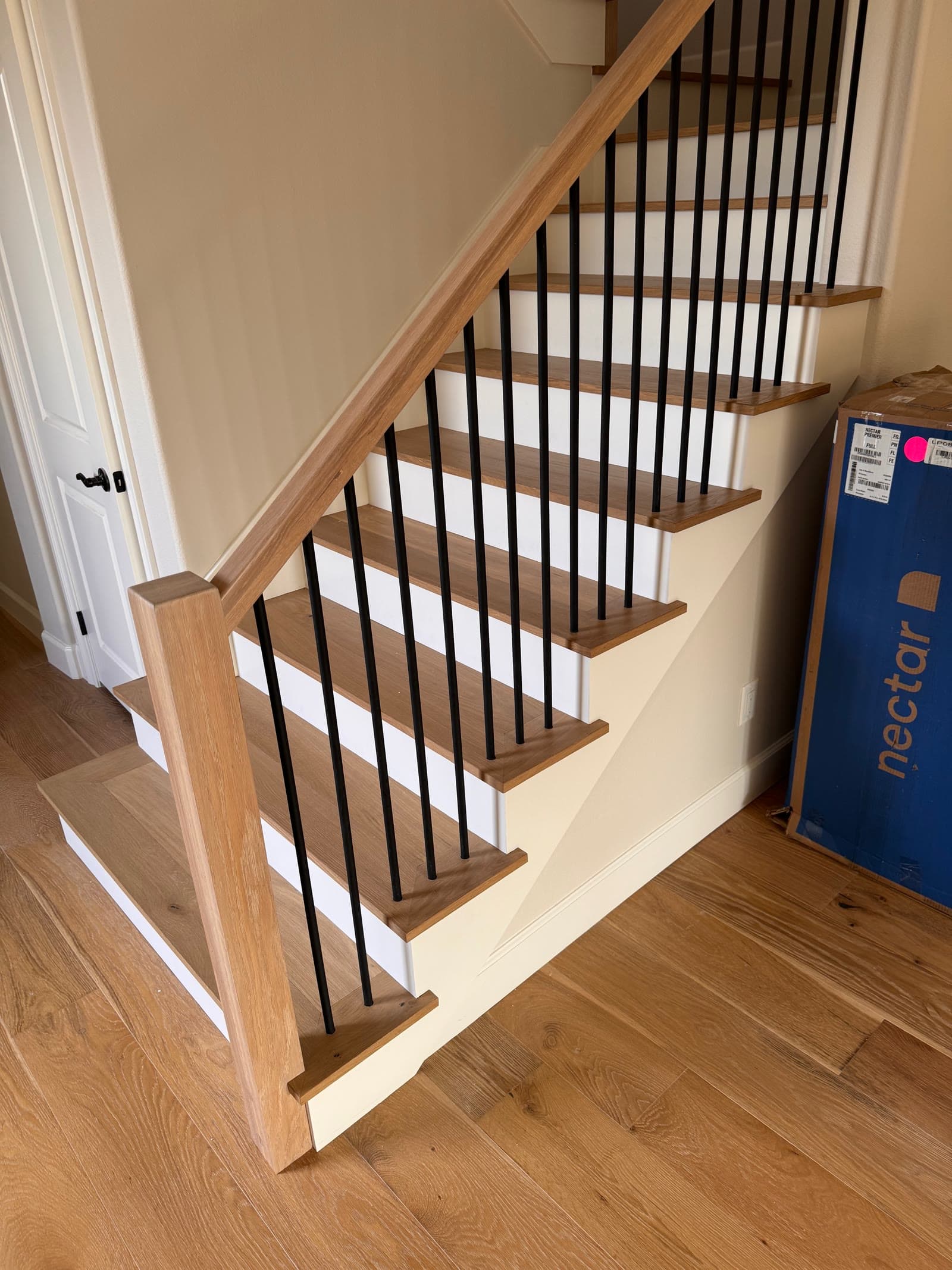 Open staircase with white oak treads, square oak newel post and black metal spindles