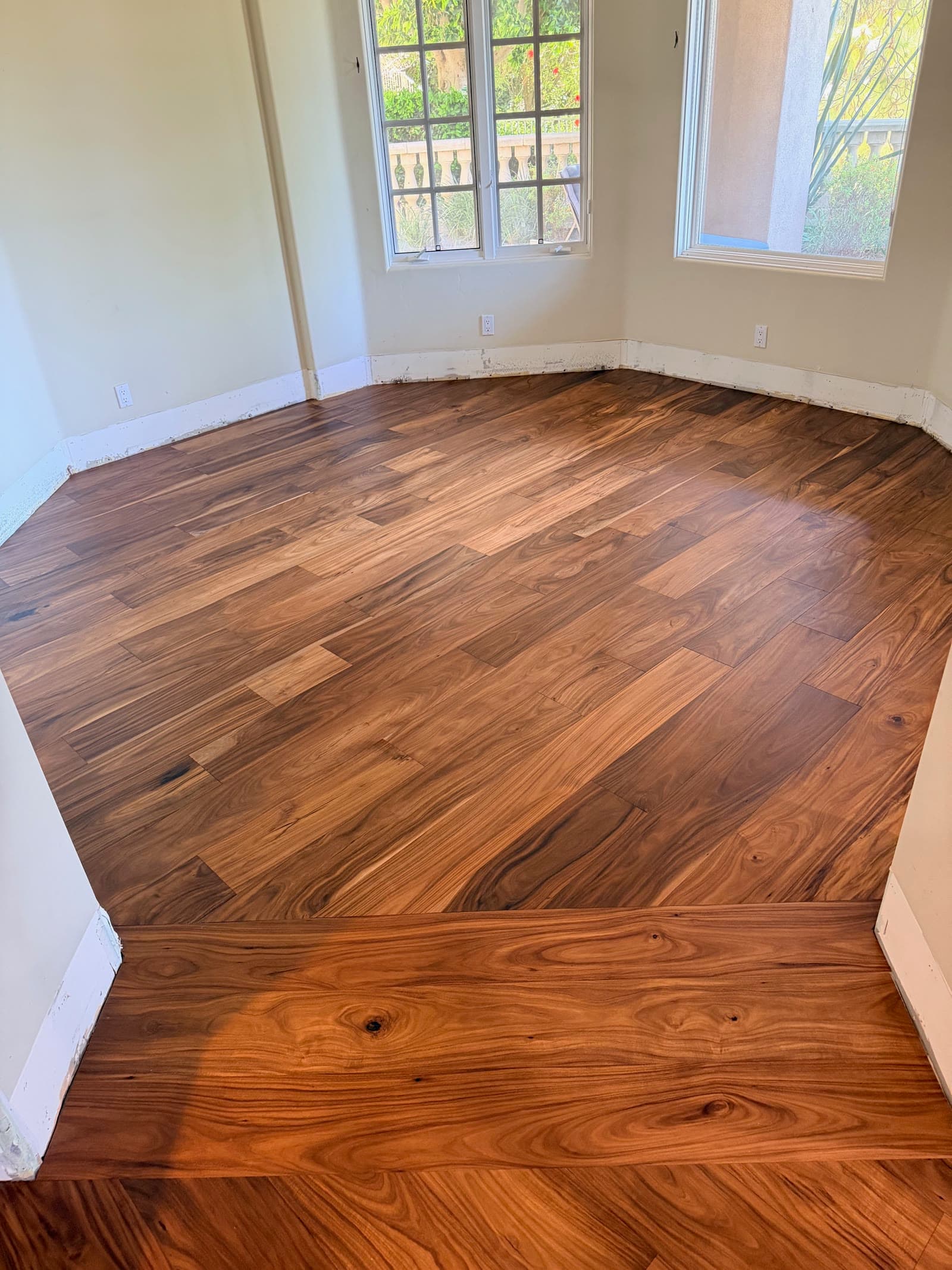 Wide-plank acacia hardwood floor in an empty Carmel Valley room with divided-light windows