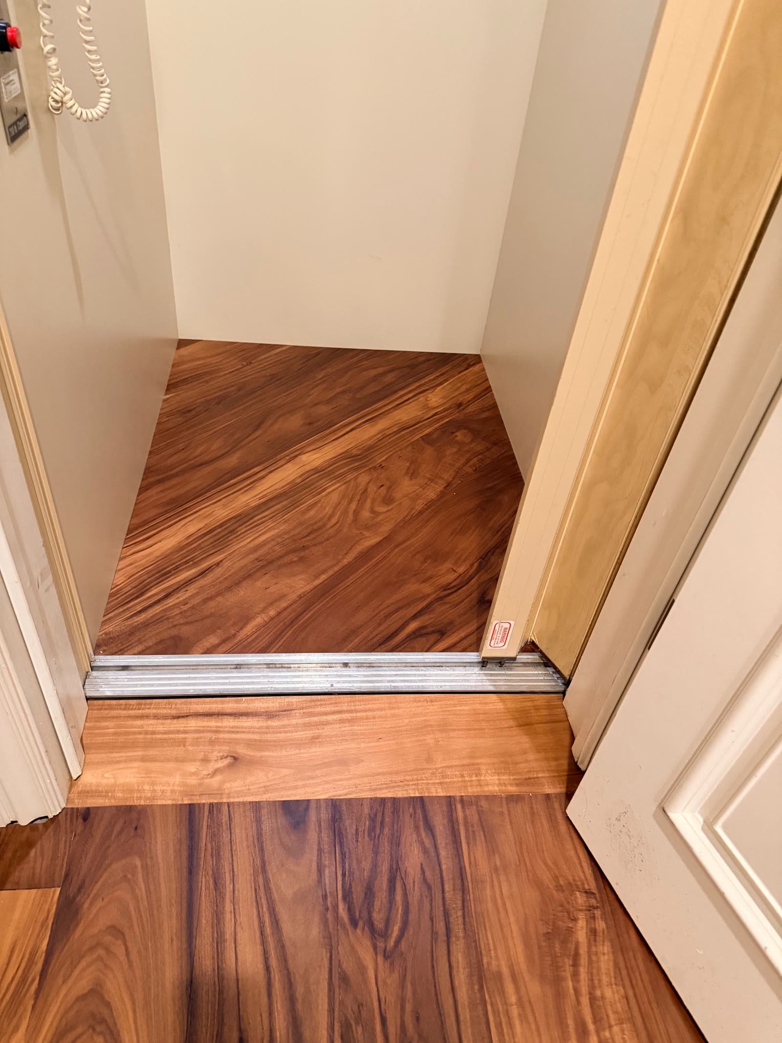 Dark figured acacia plank running through a doorway over an aluminum threshold