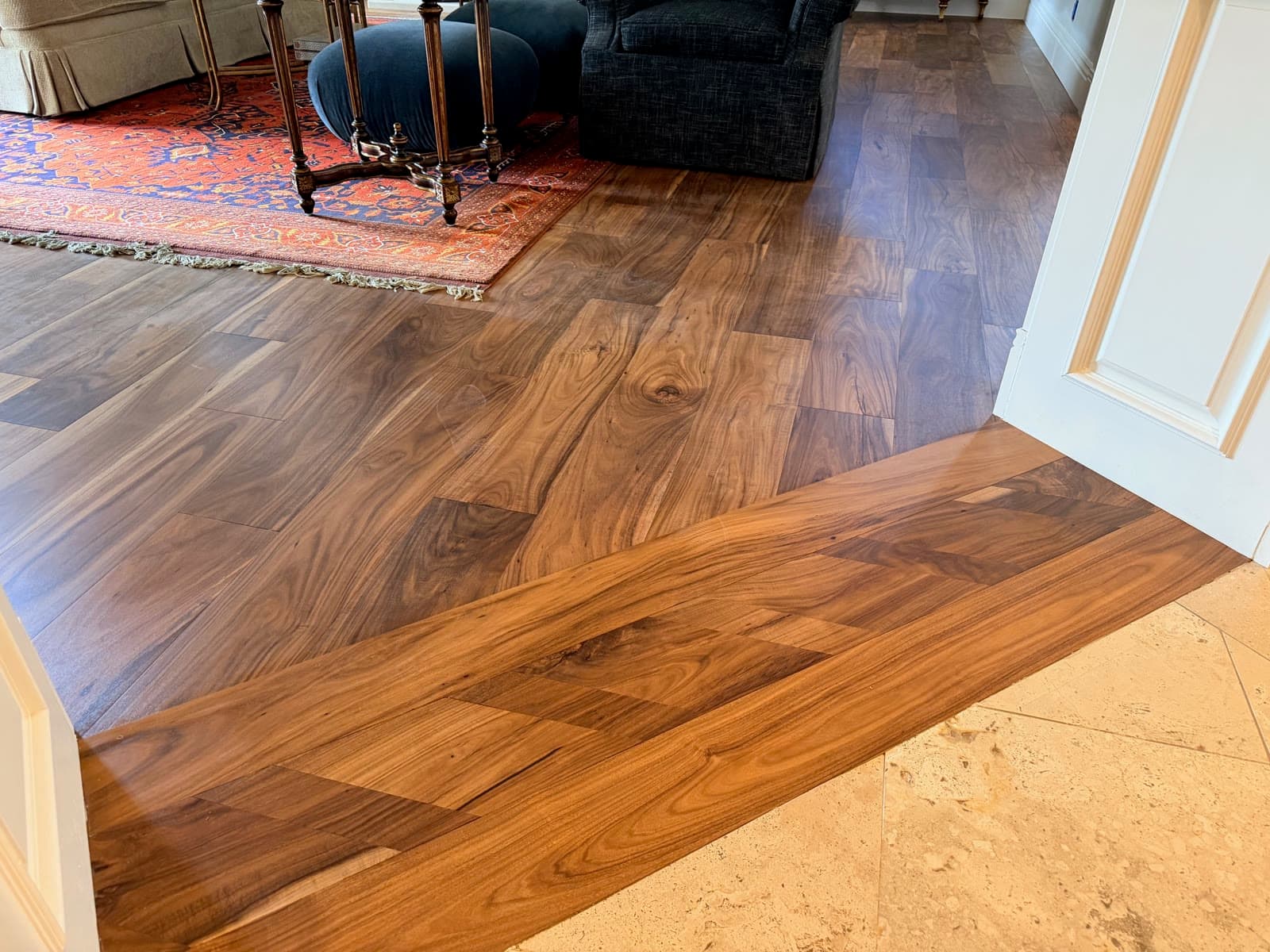 Acacia plank floor meeting travertine tile at a Carmel Valley room opening