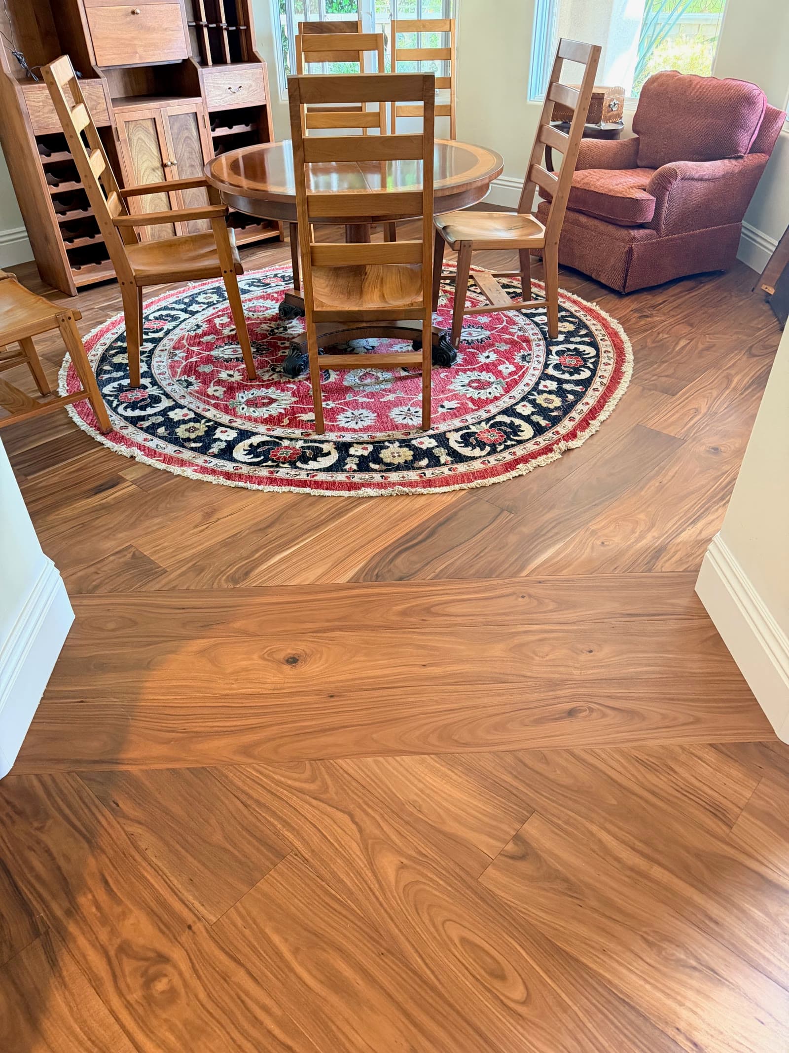 Acacia hardwood floor in a Carmel Valley dining room with a round rug and wine cabinet