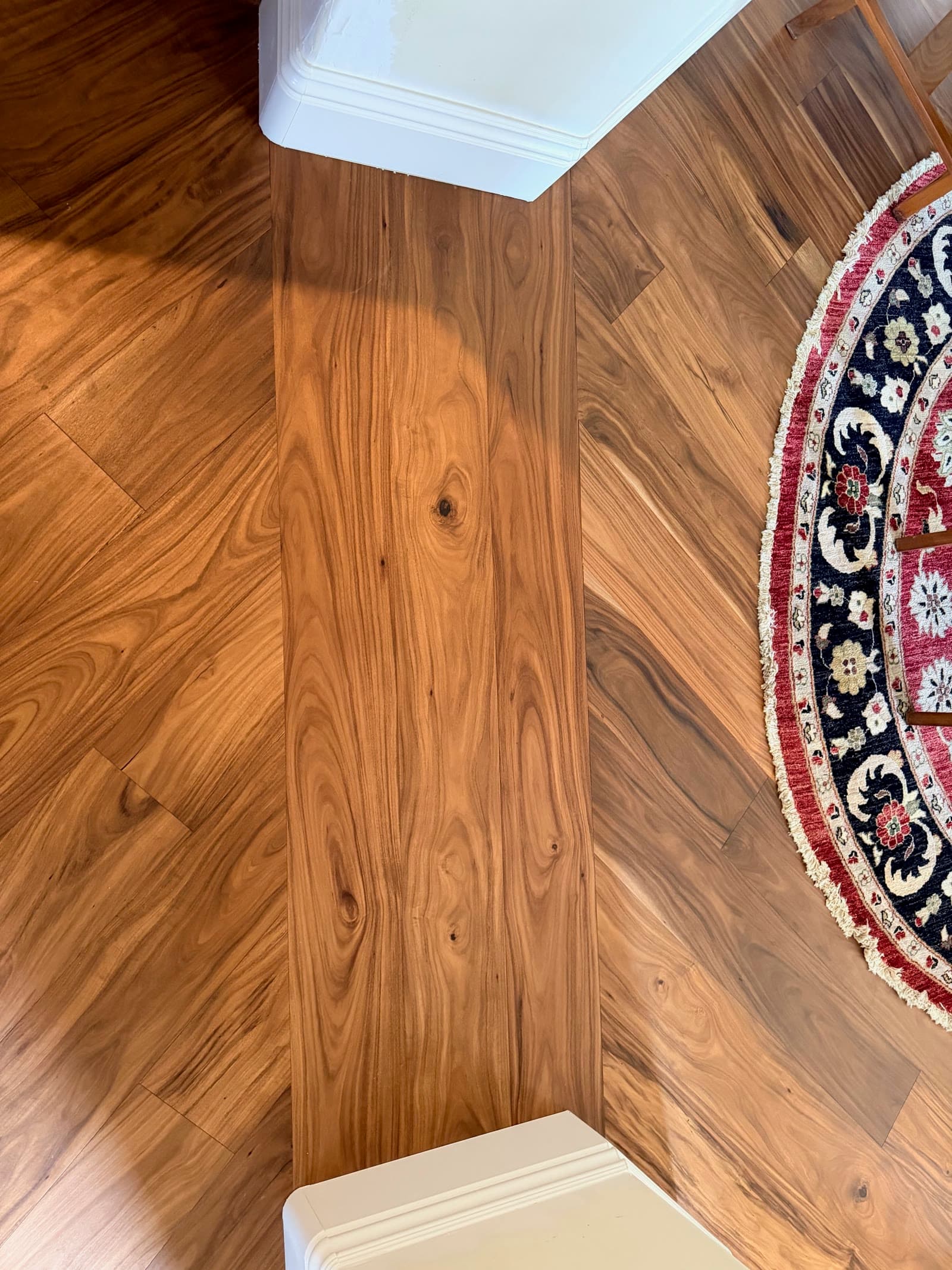Overhead view of acacia plank scribed around two painted cabinet bases