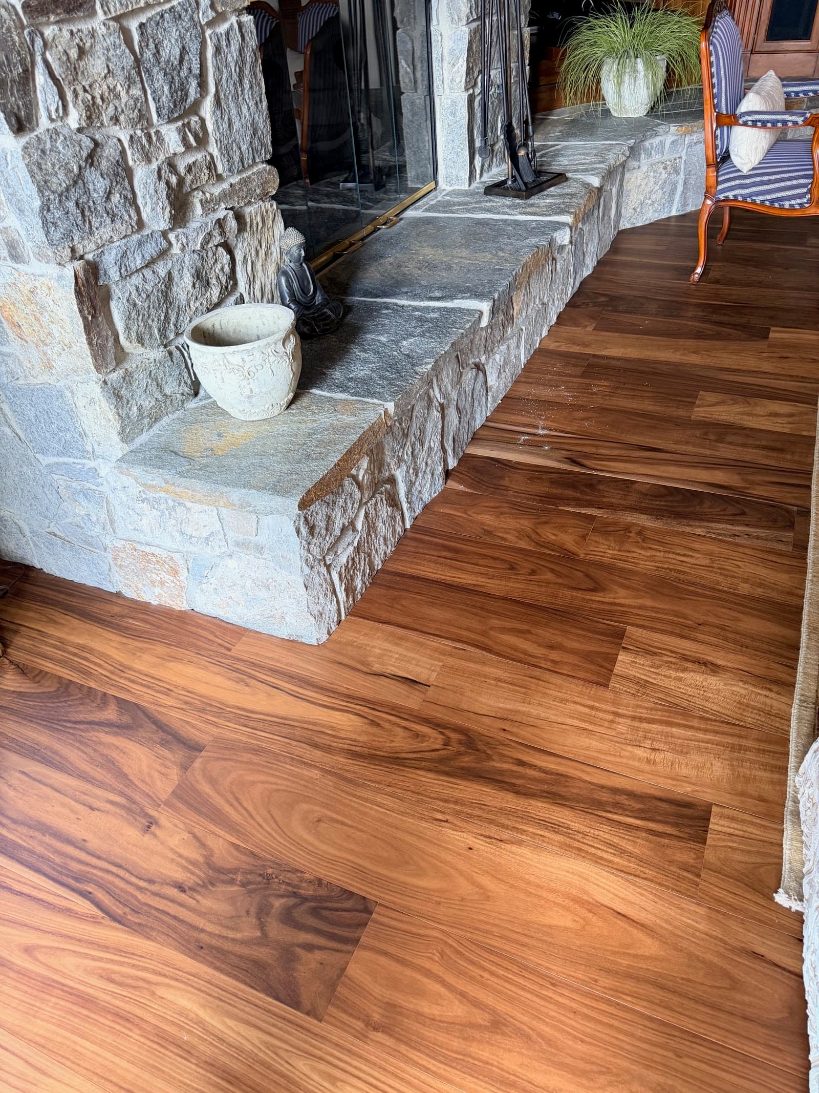 Acacia plank floor laid up to a rough stone fireplace hearth in Carmel Valley