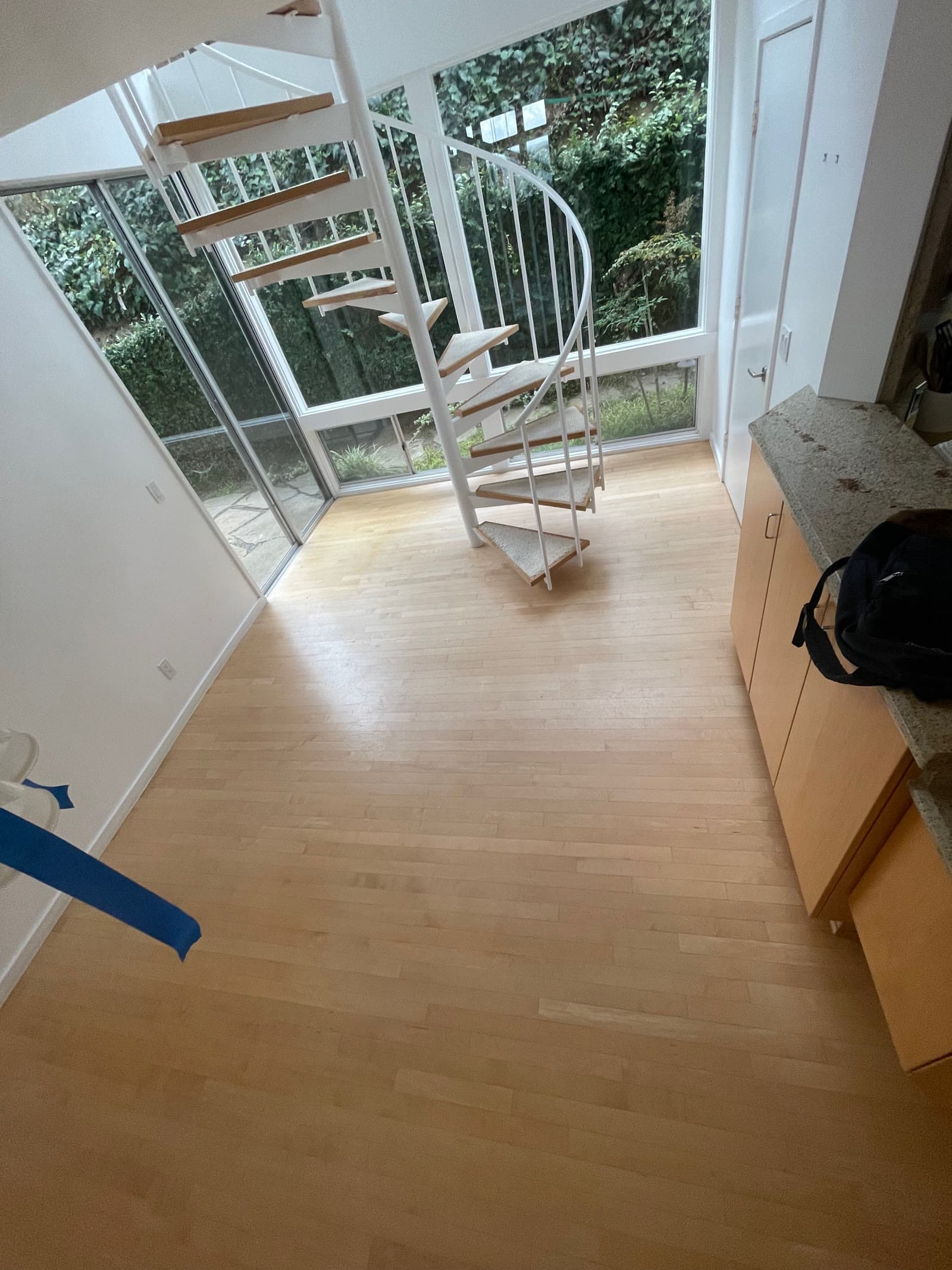 Maple strip floor in a Del Mar room with a white spiral stair and full-height glass