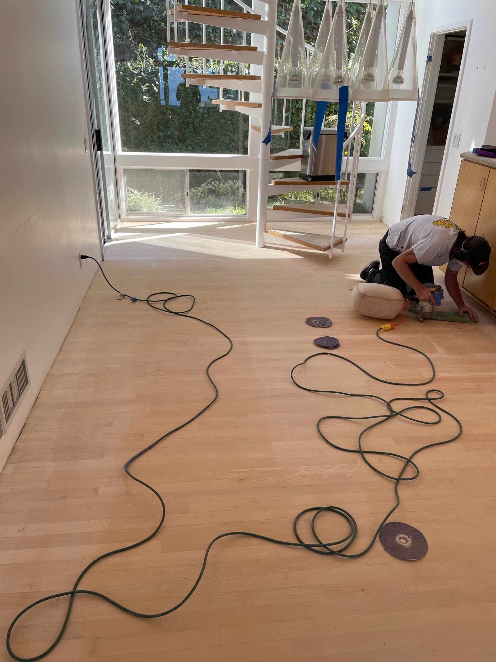 Installer in a respirator running an edger over a maple floor during refinishing in Del Mar