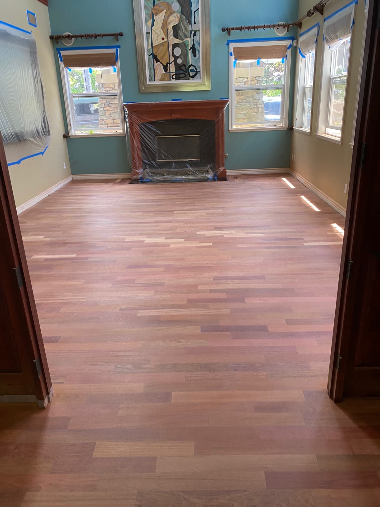 Bare sanded strip hardwood floor in a teal Encinitas dining room with the fireplace masked off