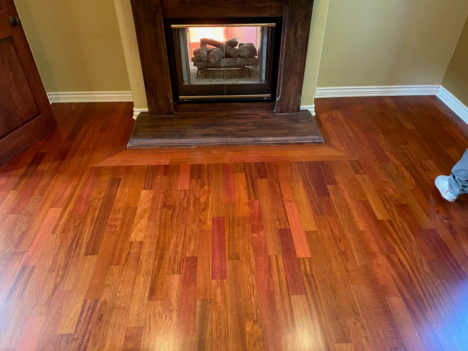 Refinished Brazilian cherry floor around a dark wood fireplace hearth in Encinitas