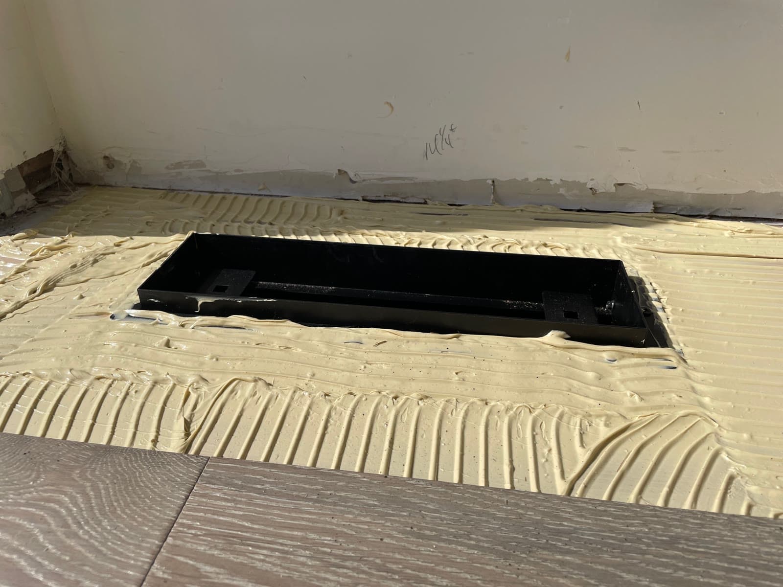 Notched trowel adhesive spread around a floor vent boot before plank goes down