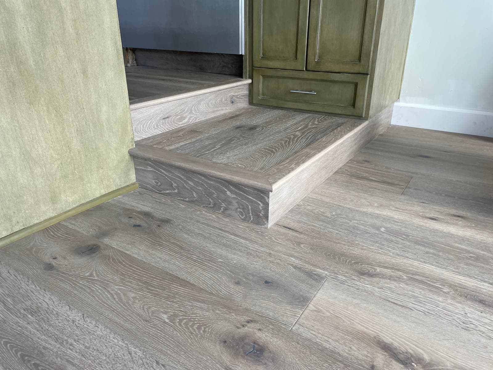 Gray driftwood-toned white oak floor with a single step down and a mitered nosing