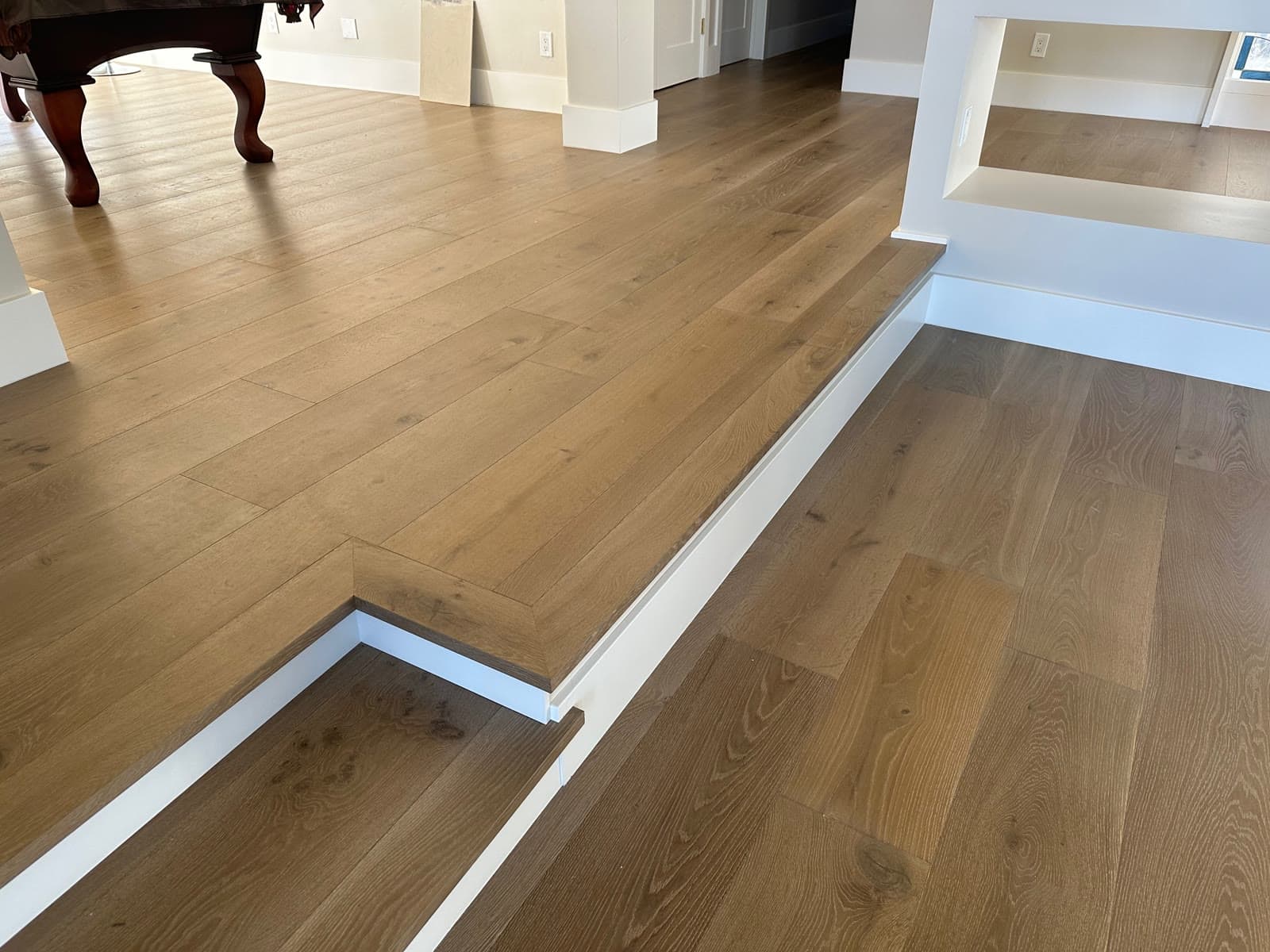 Golden white oak plank floor with a step-down landing and white painted risers, Encinitas