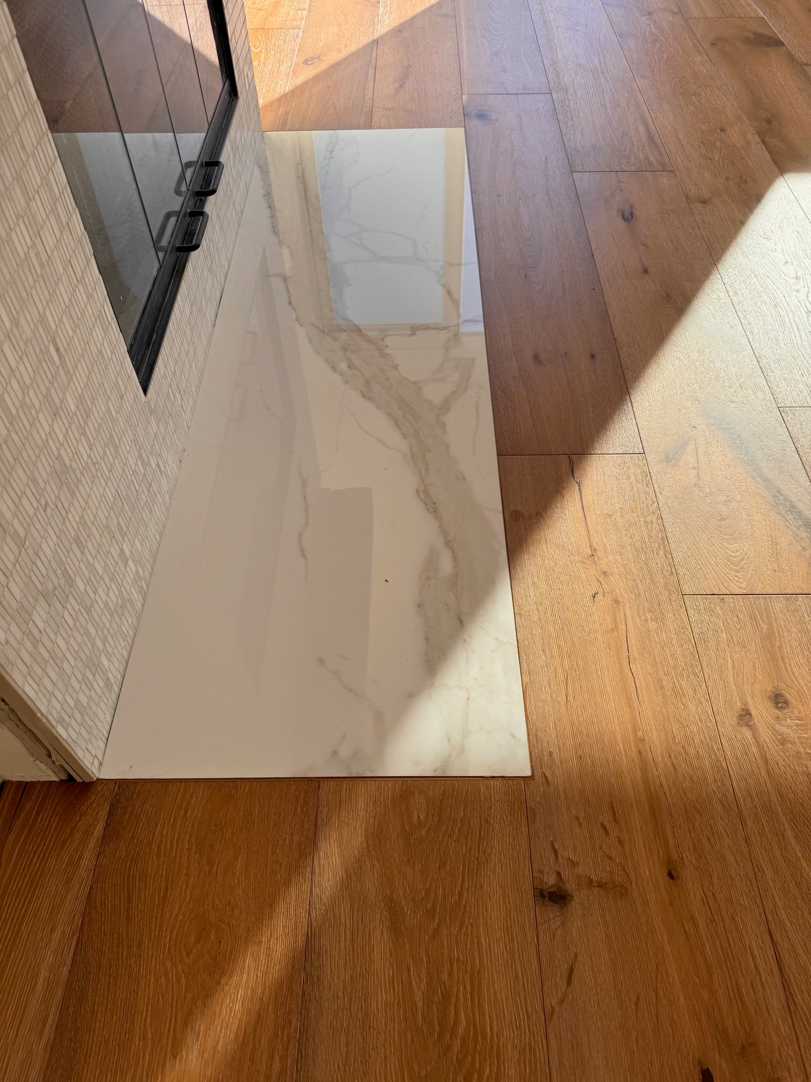 White oak plank floor set flush against a polished marble-look hearth slab