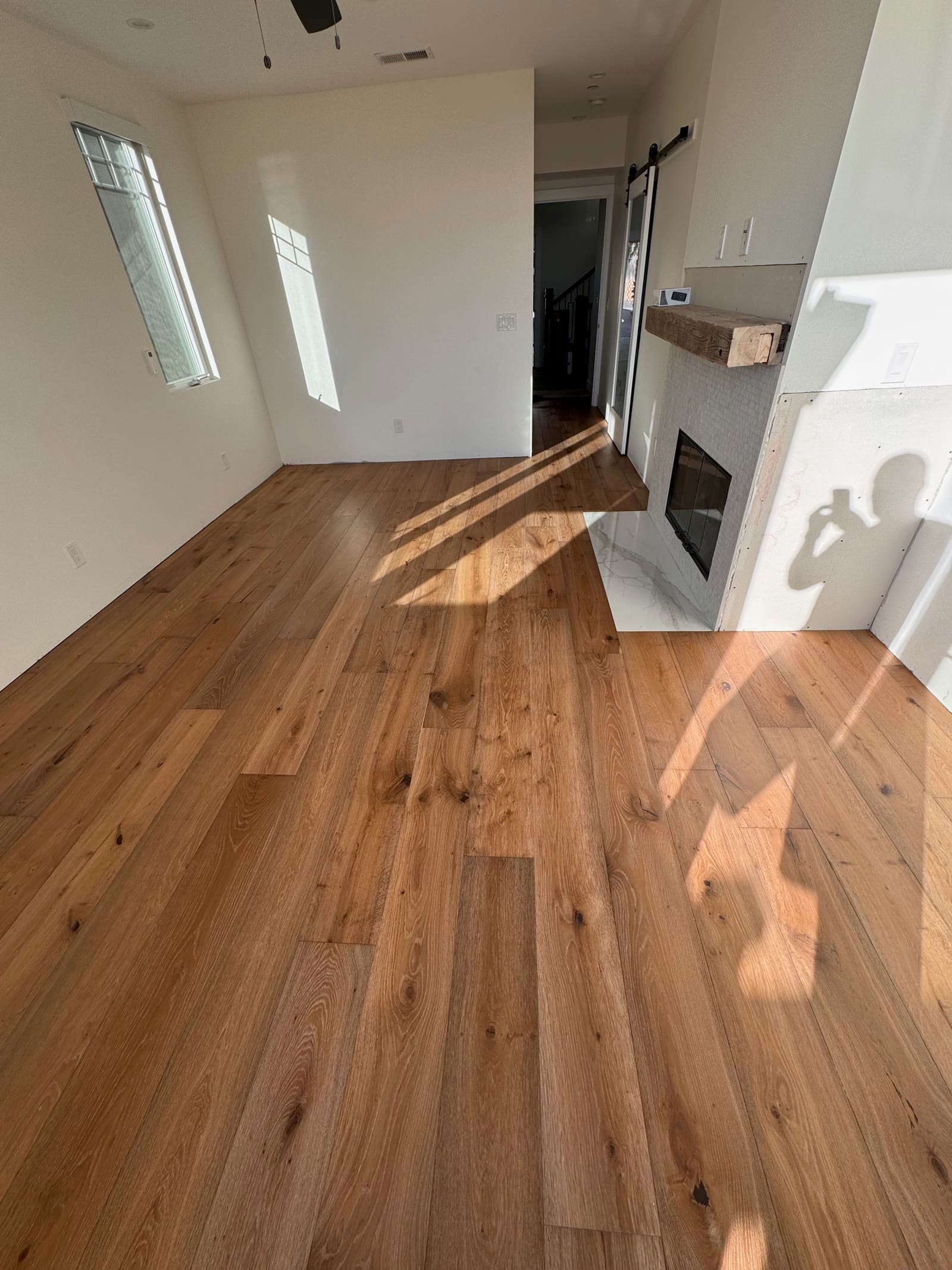 Rustic wide-plank white oak floor in a new Encinitas build with a reclaimed timber mantel