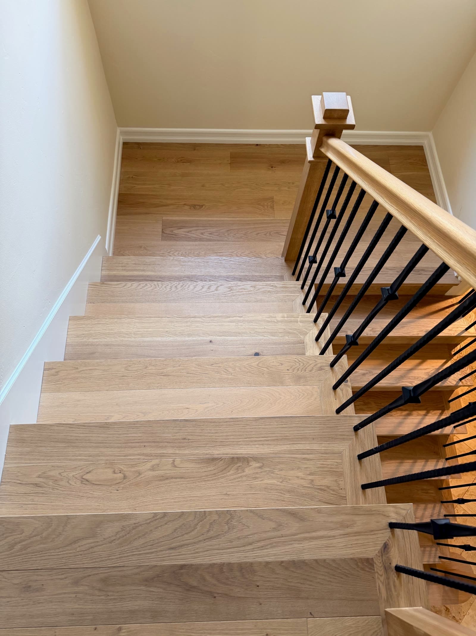 Natural white oak stair treads and risers with an oak handrail and black iron balusters, Encinitas