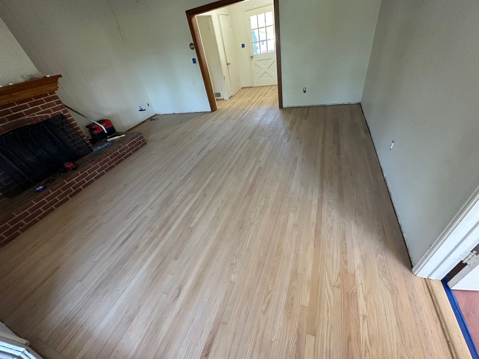 Fully sanded bare red oak floor in a La Jolla living room with a brick fireplace