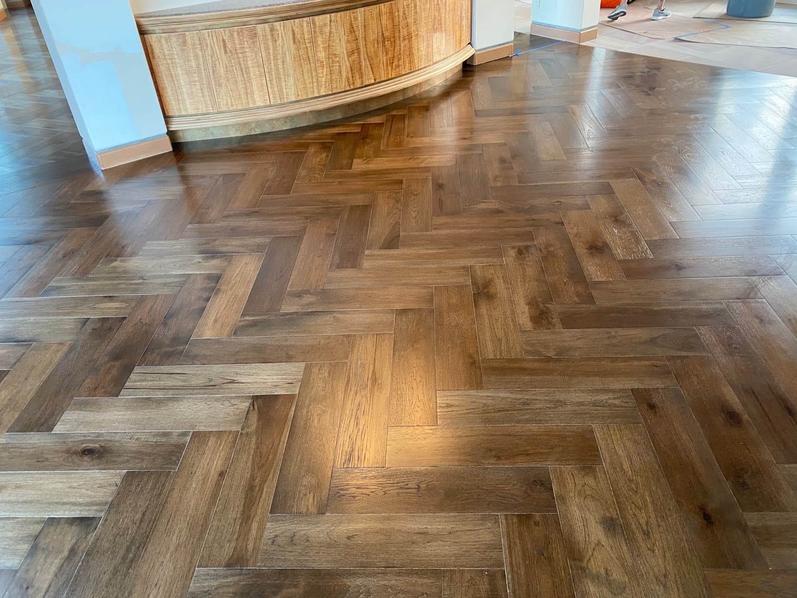 Warm brown herringbone floor curving around a wood-paneled bar base in Rancho Santa Fe