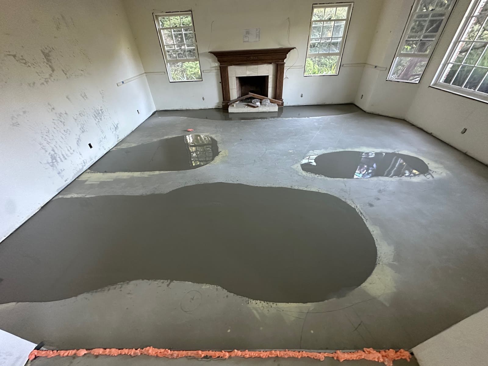 Self-leveling compound poured in patches across a slab in a stripped Rancho Santa Fe room