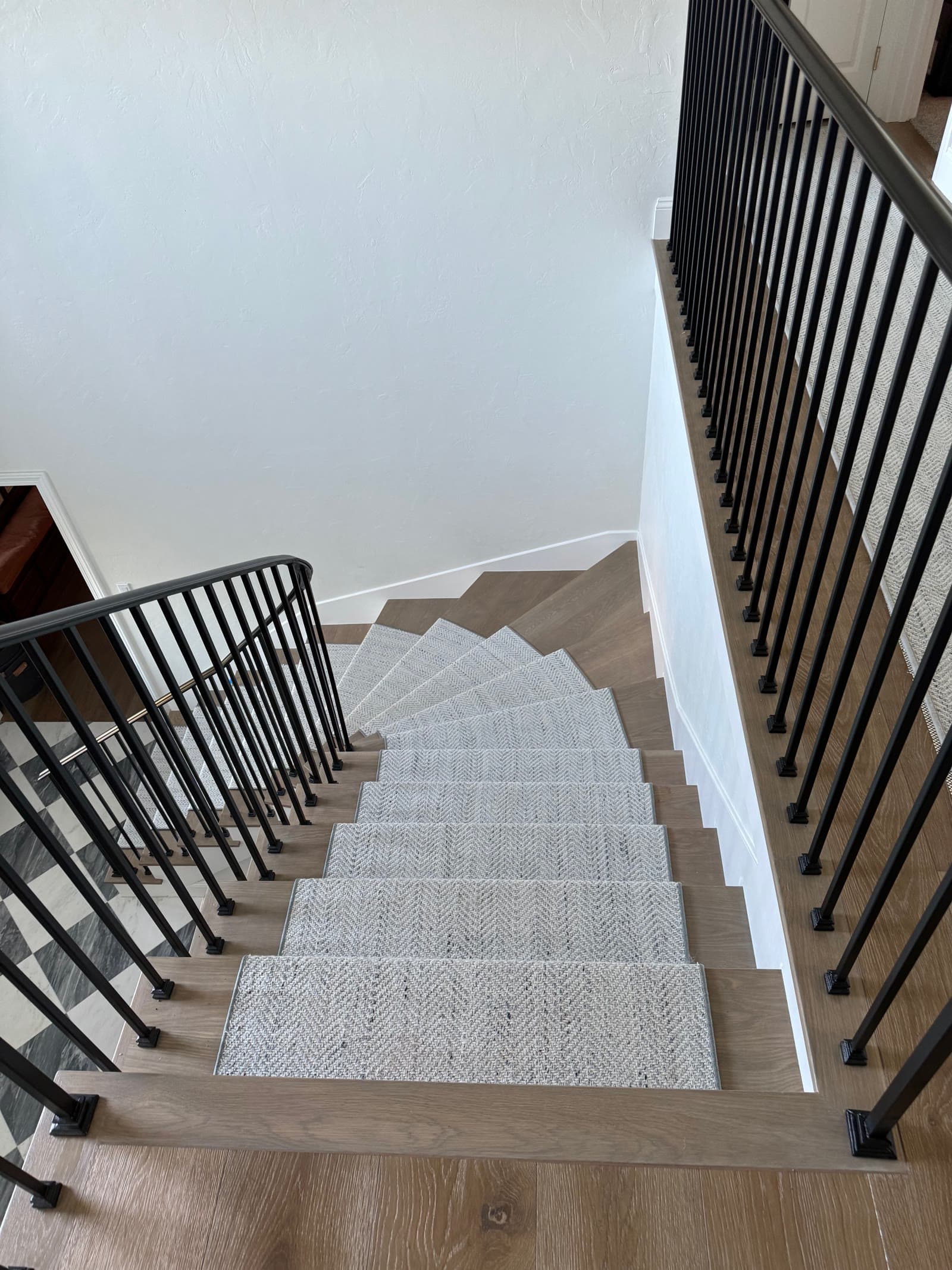 Curved winder staircase in white oak with a herringbone-weave runner, seen from above