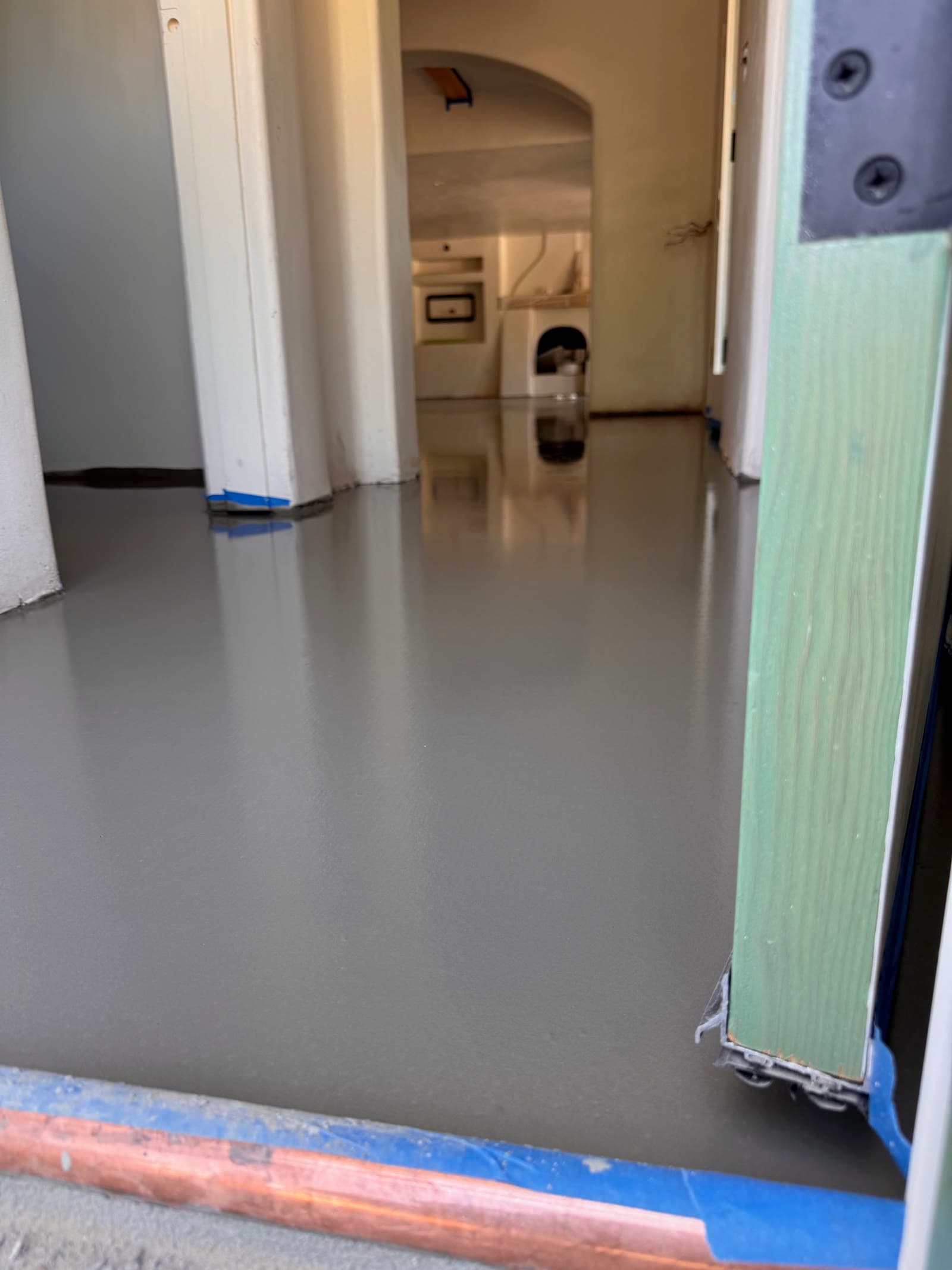 Gray self-leveling underlayment curing across a hallway slab in Rancho Santa Fe