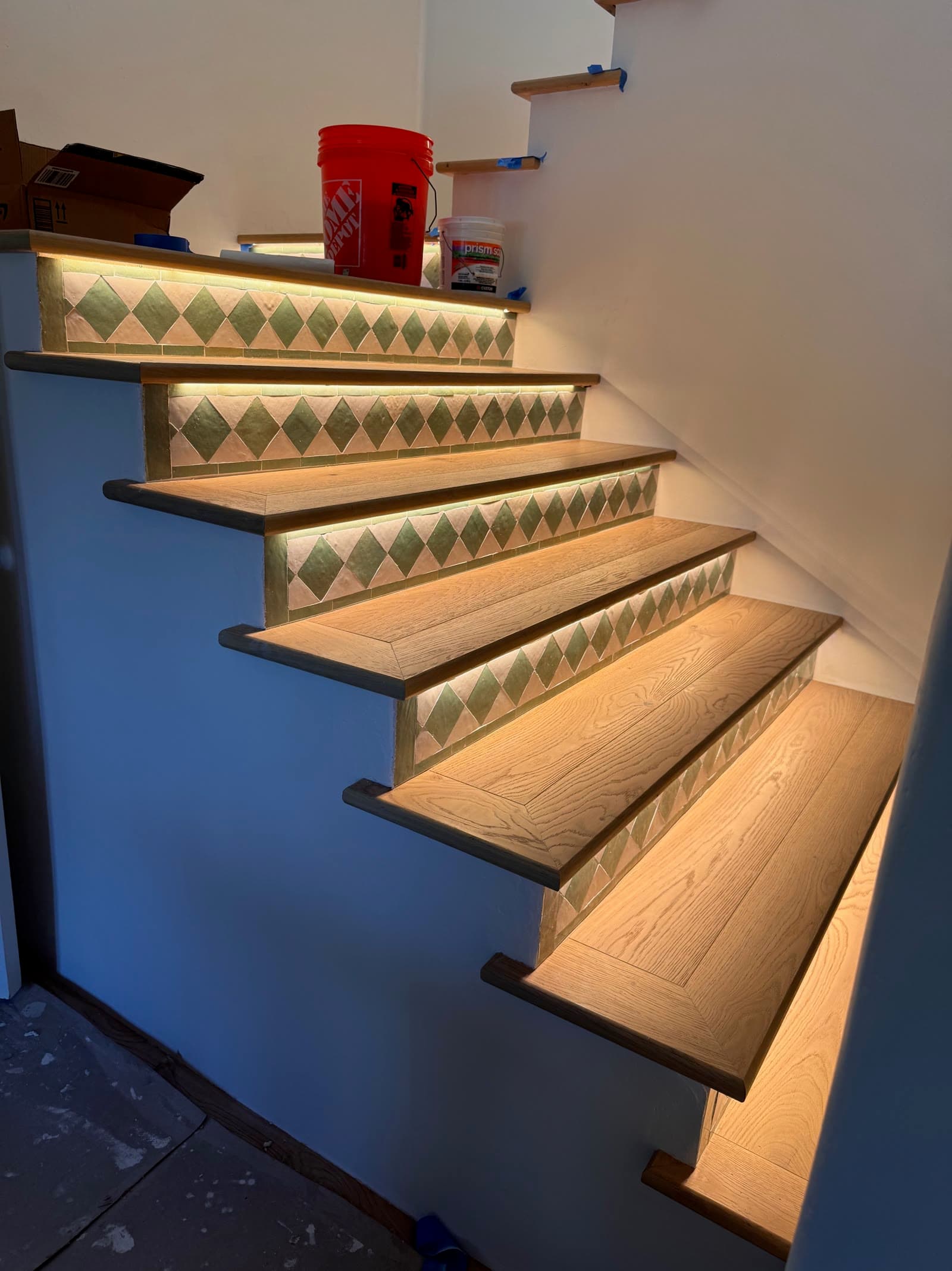 White oak stair treads over green and white Spanish tile risers with LED strip lighting