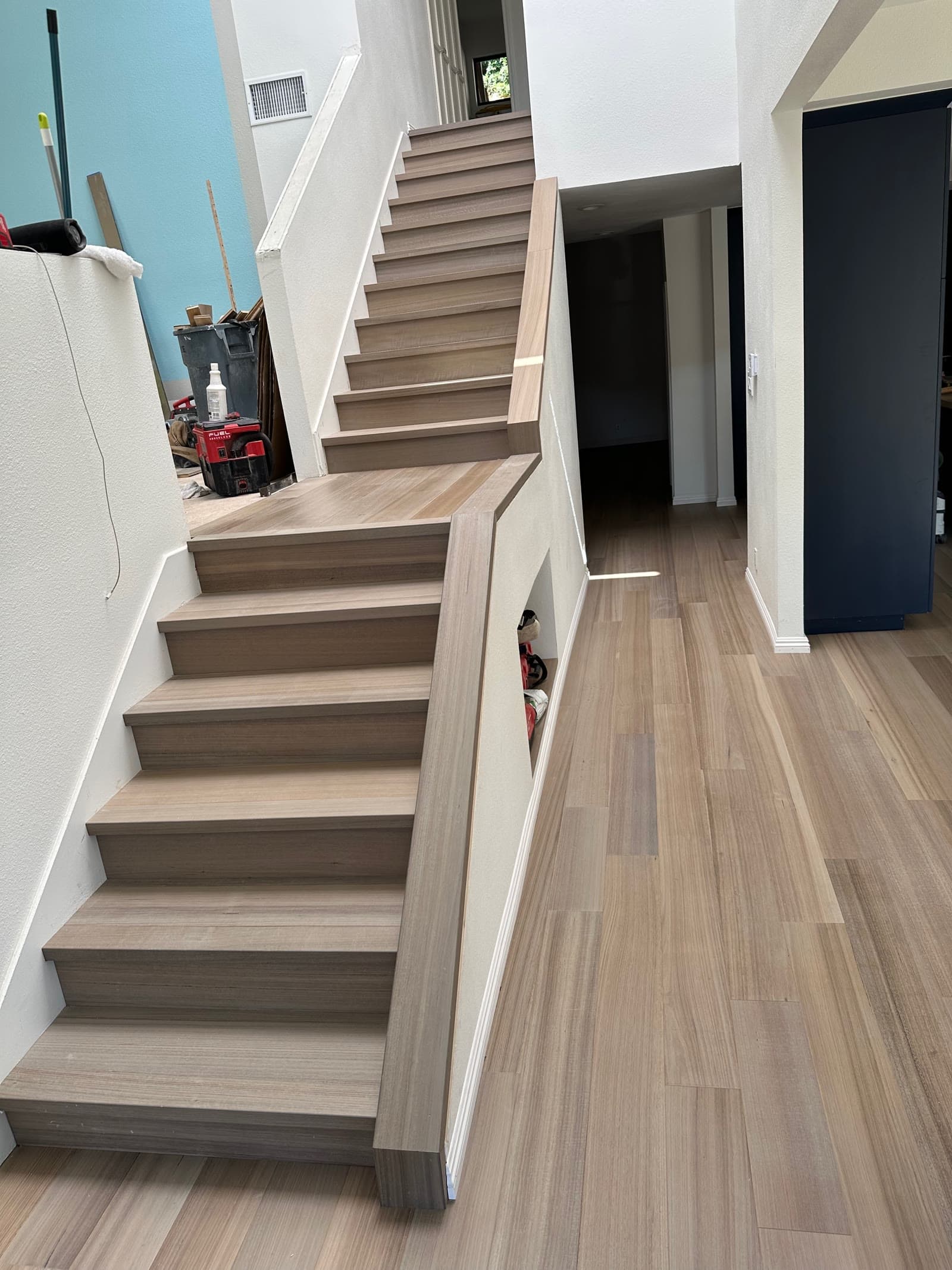Staircase with pale plank treads and a box newel under construction in San Diego