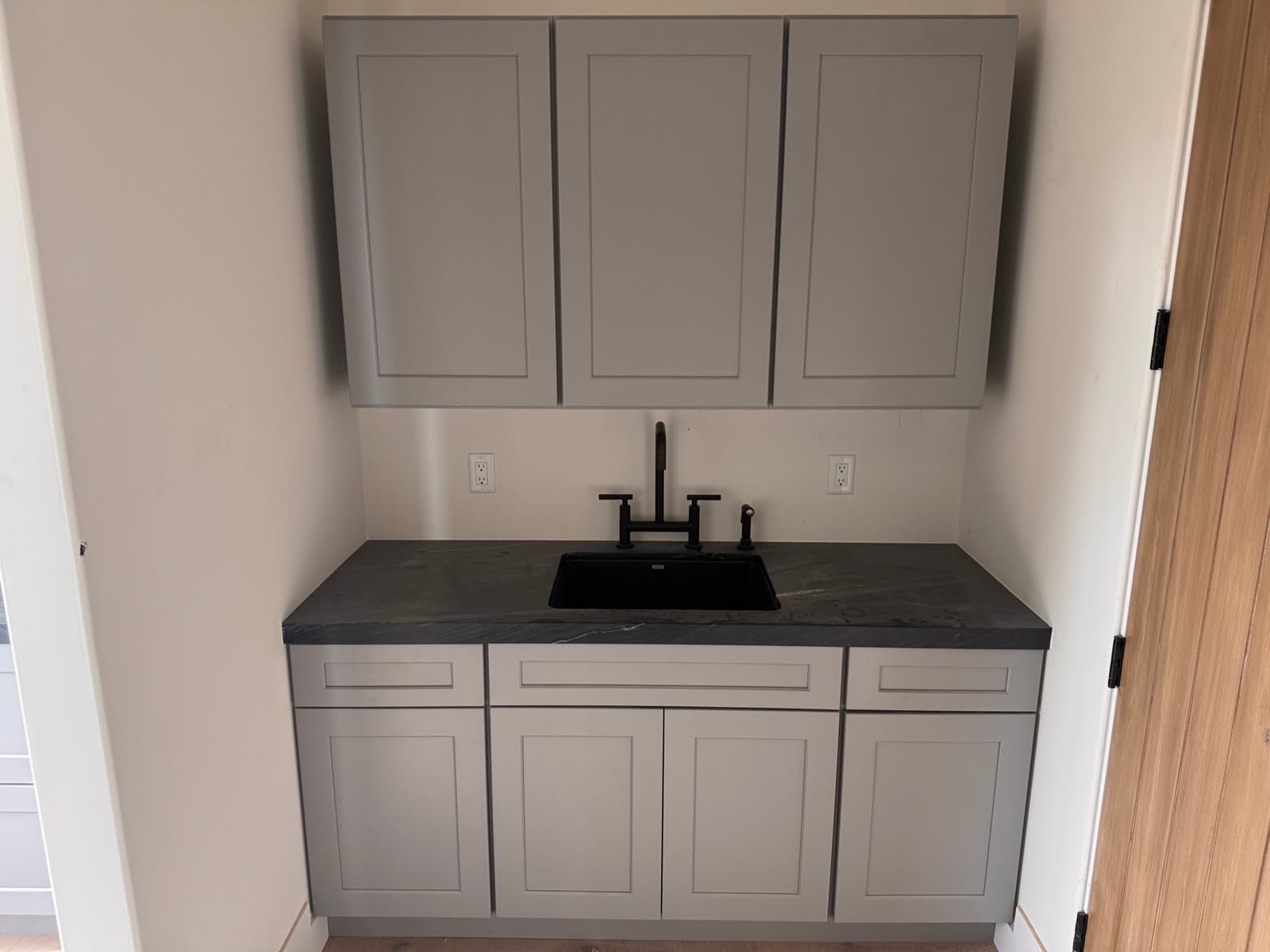 Gray shaker cabinets with a soapstone counter and black bar sink in San Diego