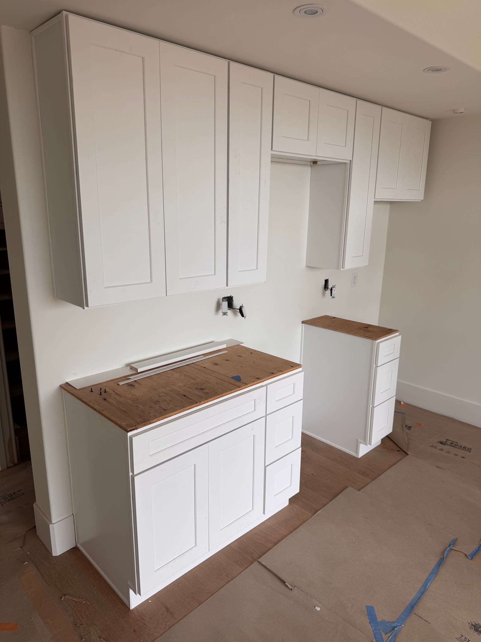 White shaker cabinets installed with temporary plywood tops in a San Diego kitchen