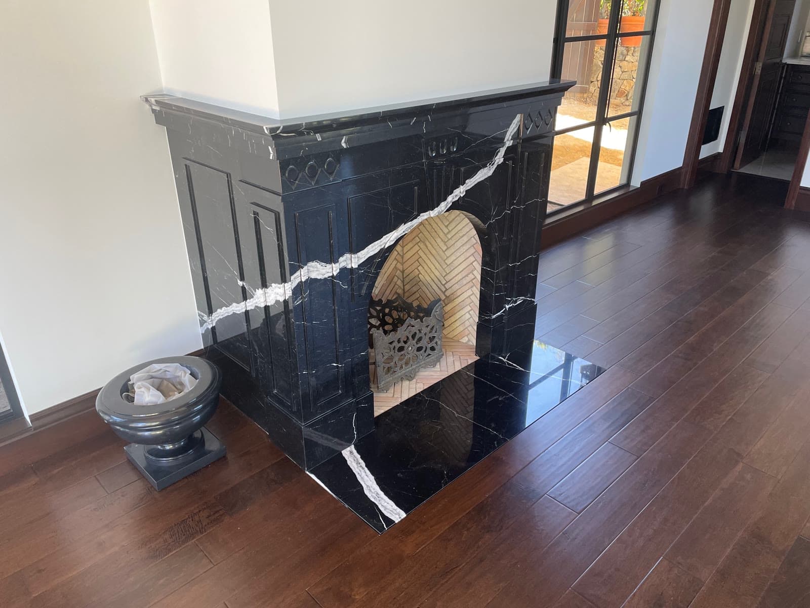 Dark stained hardwood floor around a black marble fireplace surround