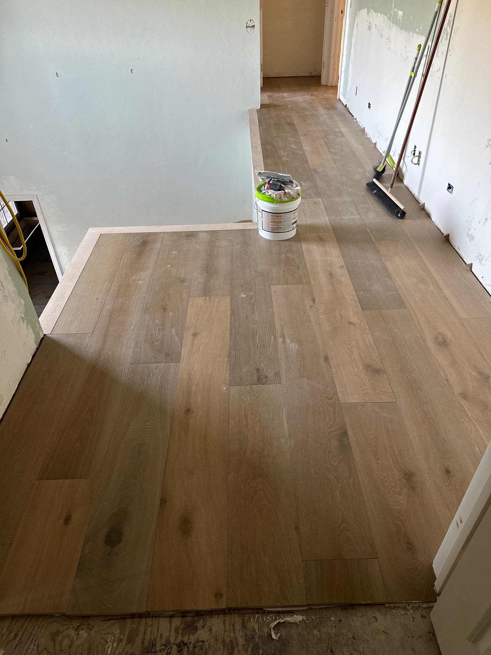 White oak plank floor half laid over a plywood subfloor during installation
