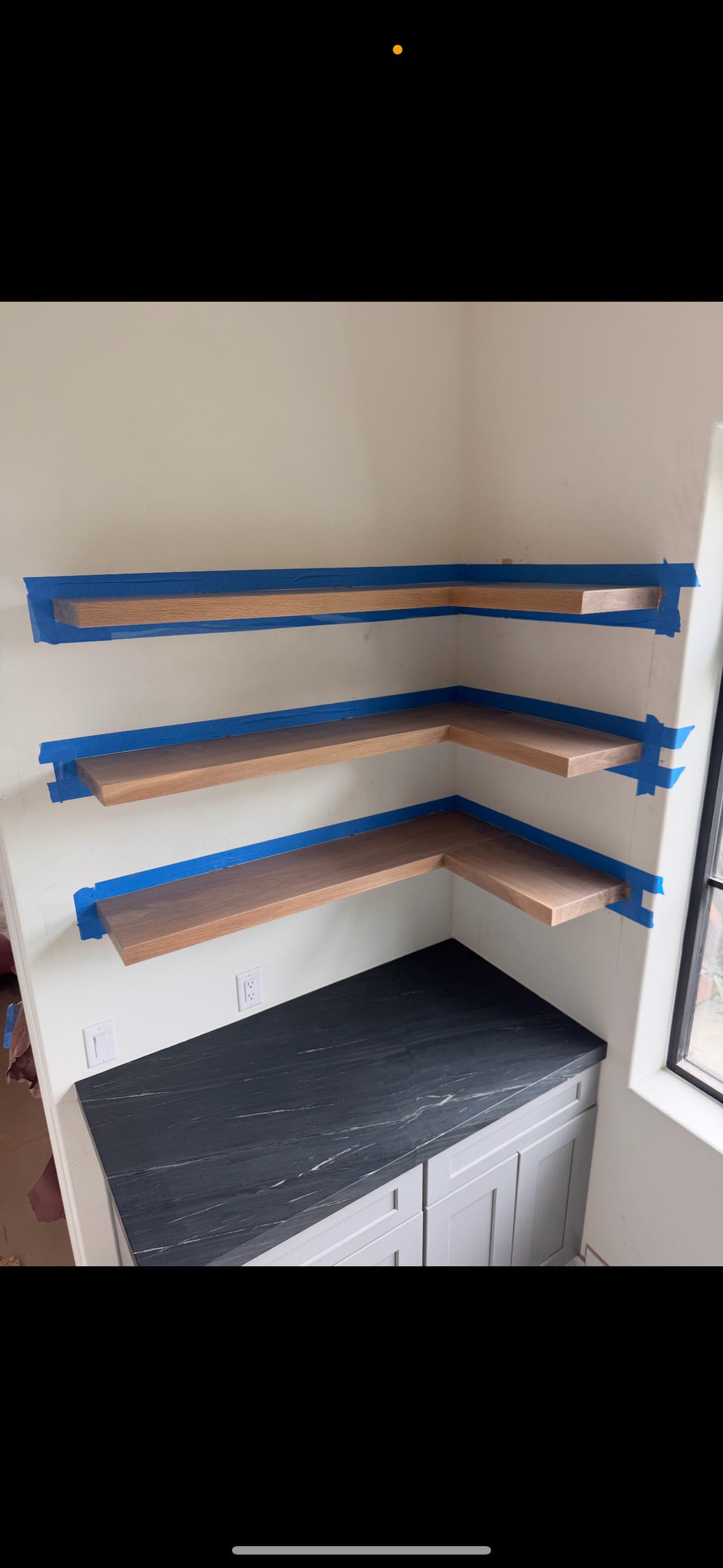White oak floating shelves clamped up over a soapstone counter during installation