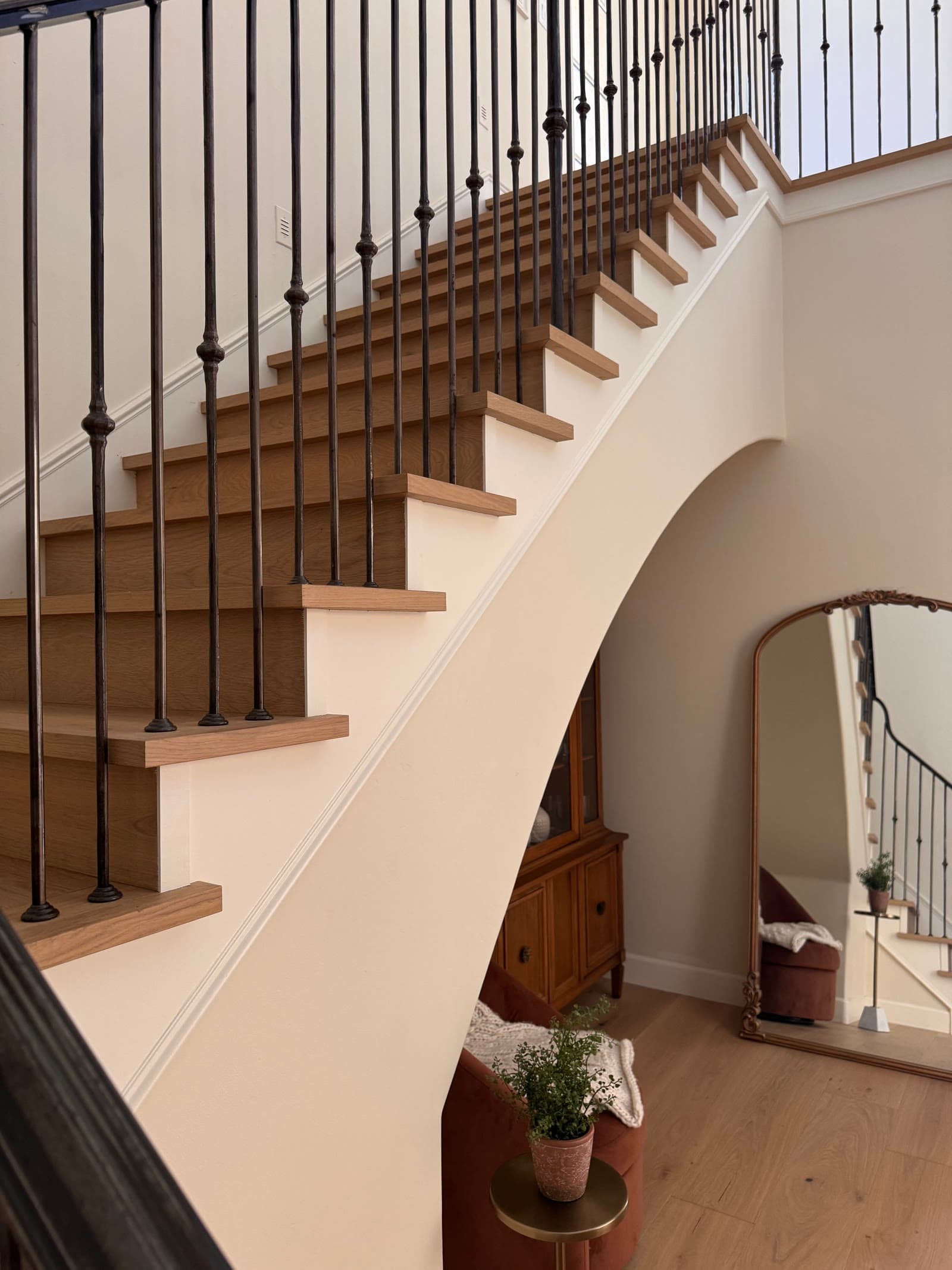 Open-stringer staircase with white oak treads and wrought iron balusters in Santaluz
