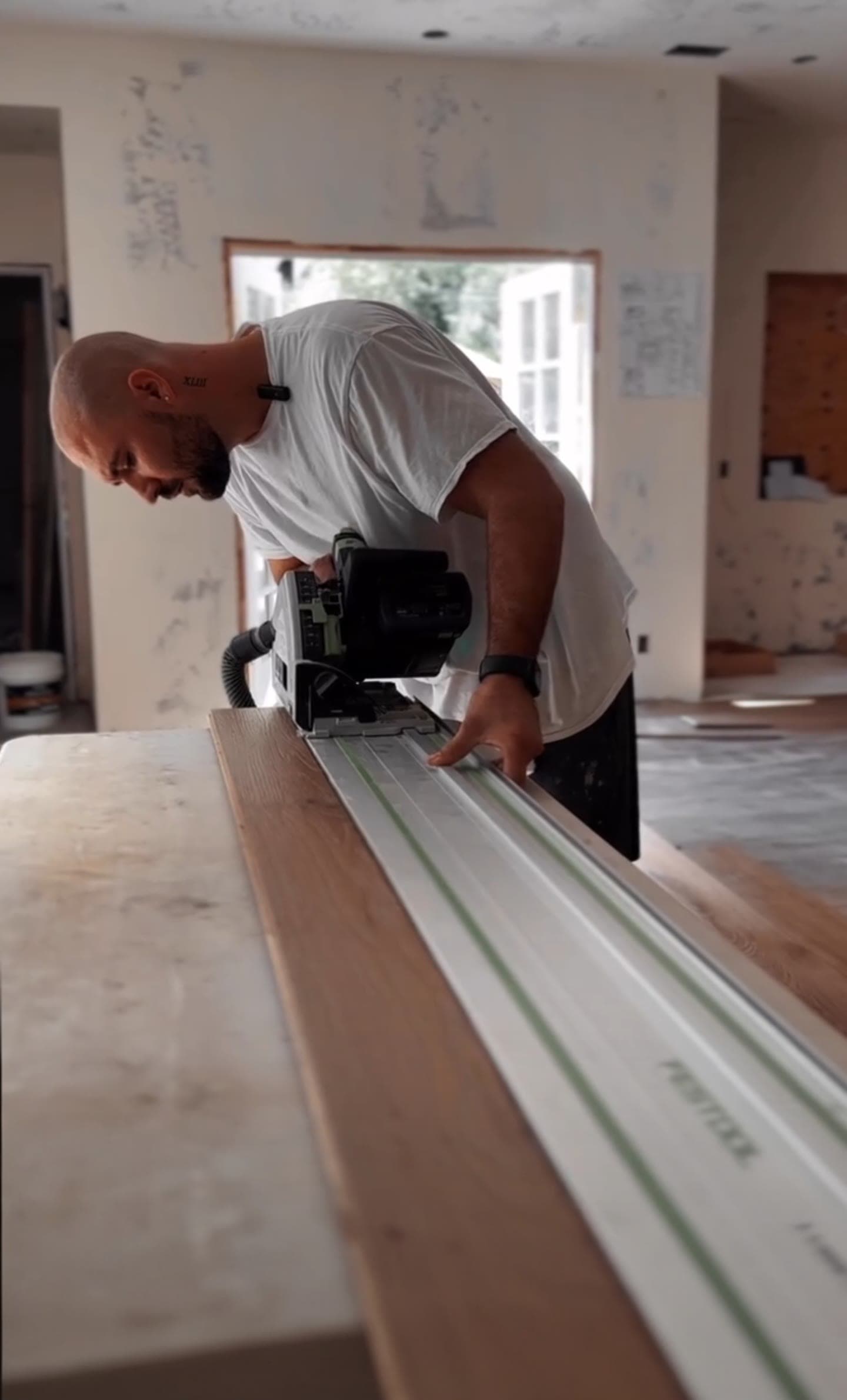Stone Peters cutting a white oak plank with a track saw on a job site