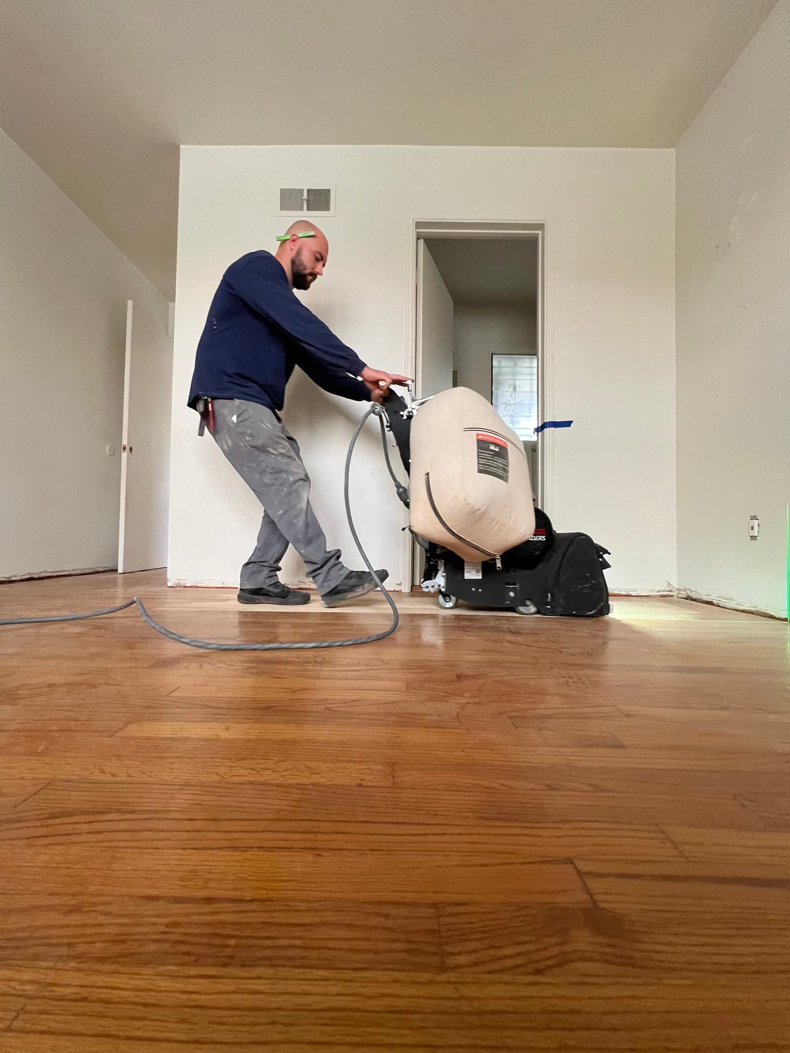 Stone Peters running a drum sander across a hardwood floor in La Jolla