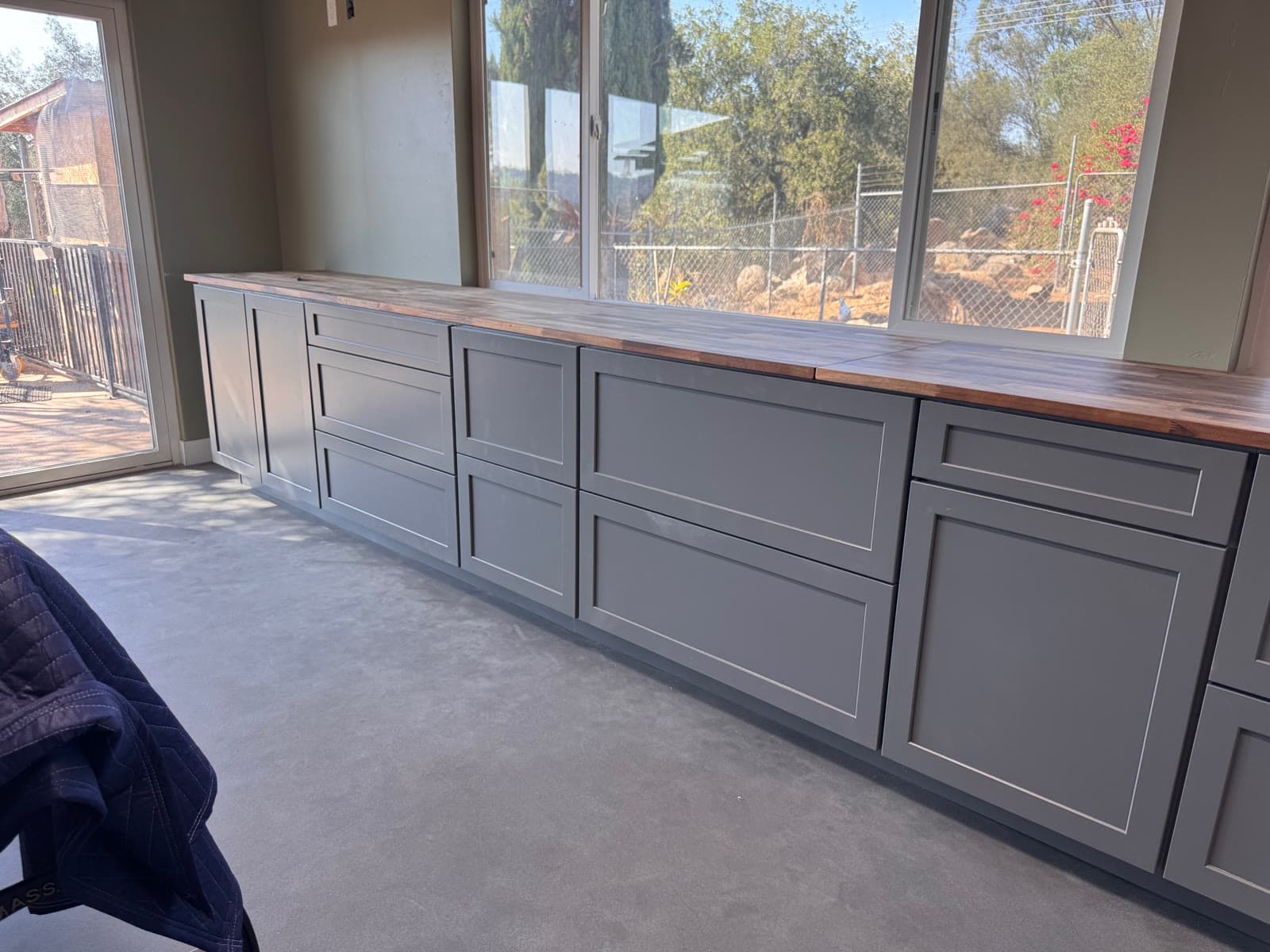 Gray shaker cabinetry with butcher block counter over a sealed concrete floor in Valley Center