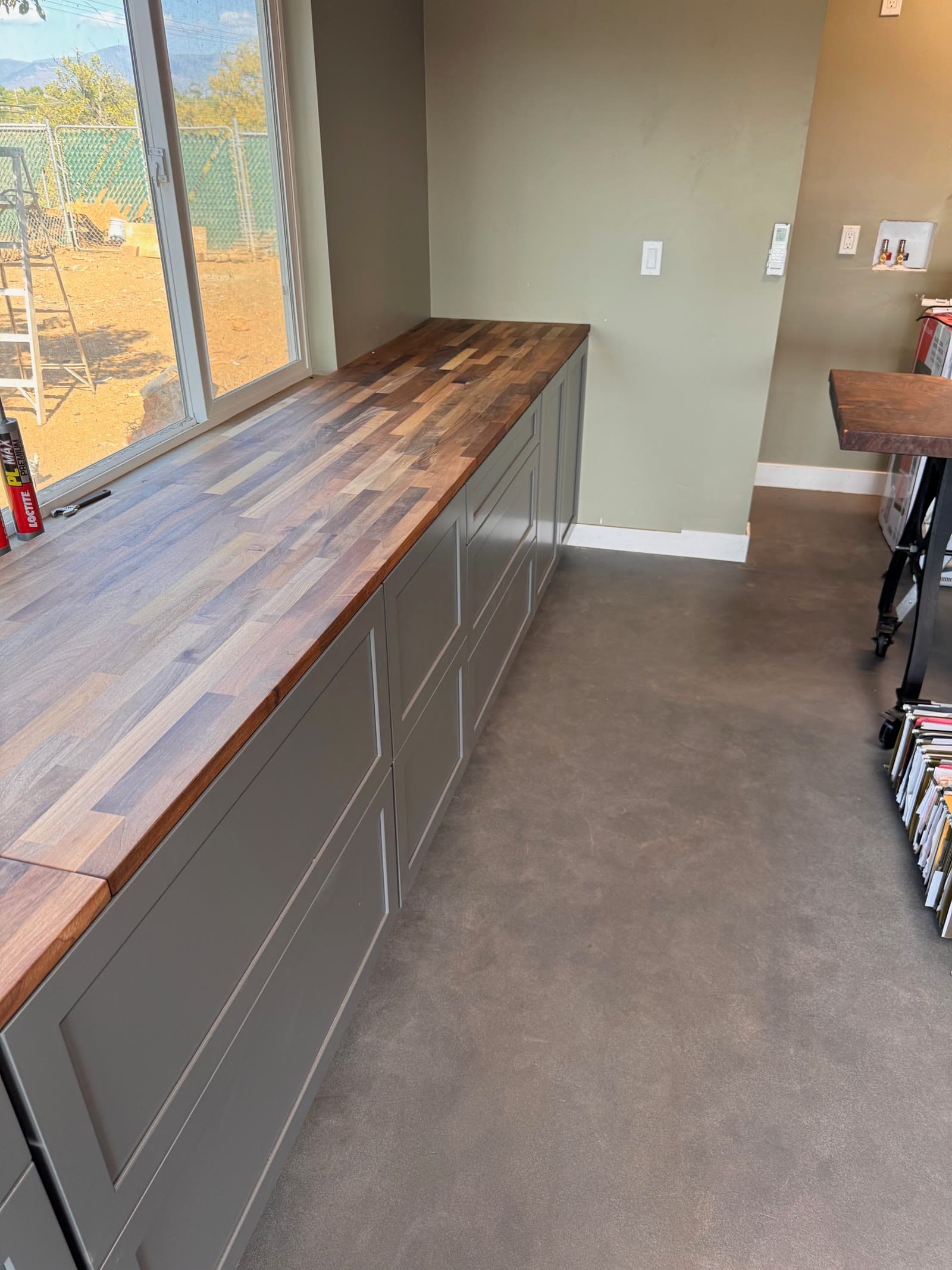 Walnut butcher block counter on gray cabinets above a polished concrete floor, Valley Center