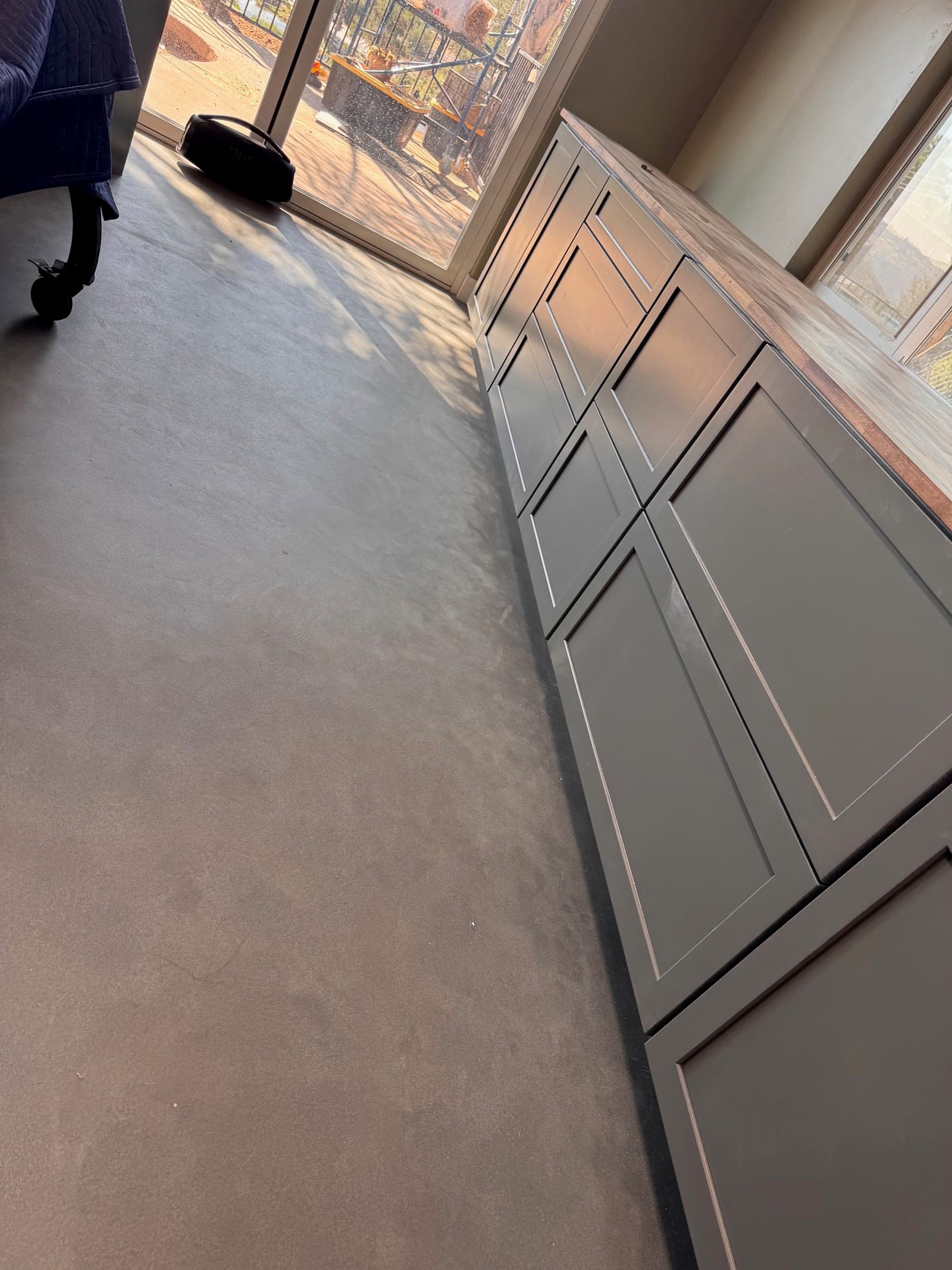 Sealed concrete floor running under a long run of dark gray shaker cabinets in Valley Center